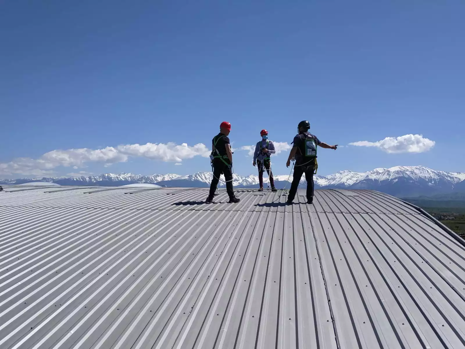 trei lucratori realizeaza lucrari pe acoperis fiind ancorati de un sistem linia vietii pe cablu de otel